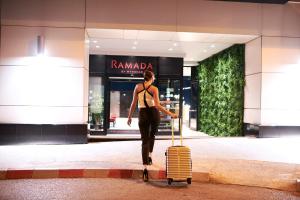 a woman walking in front of a store with a suitcase at Ramada by Wyndham Podgorica in Podgorica