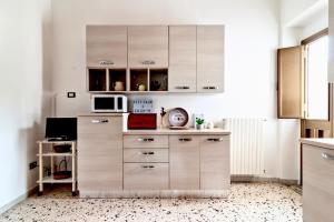 a kitchen with wooden cabinets and a microwave at La Casa di Julia in Lecce