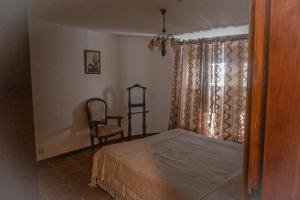 een slaapkamer met een bed, een stoel en een raam bij Casa Nova de Germil in Ponte da Barca