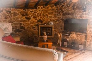 a living room with a stone fireplace and a couch at Casa Nova de Germil in Ponte da Barca
