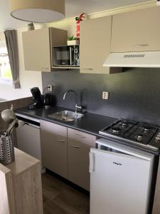 a kitchen with a sink and a stove top oven at Luxe Chalet dichtbij Zoutelande in Biggekerke