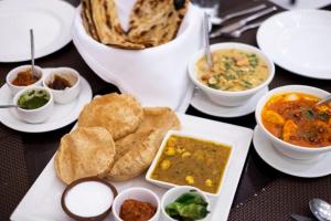 a table with plates of food and bowls of soup at HOTEL DAKSH in Chinchwad