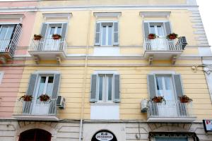 un edificio giallo con finestre e balconi con fioriti di B&B Germinario a Trani