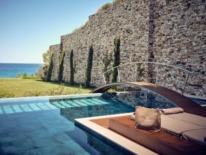 a swimming pool in front of a stone wall at Lesante Blu, a member of The Leading Hotels of the World - Adults Only in Tragaki