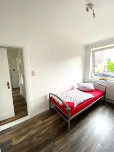 a red bed in a room with a window at Ruhige 3-Zimmerwohnung im Norden Bremens für Monteure und Geschäftsreisende in Bremen