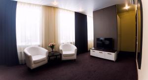 a room with two white chairs and a television at History Hotel in Vologda +37 photos