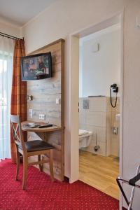 a room with a desk and a bathroom with a tub at Höhenhotel & Restaurant Kalikutt in Oppenau