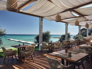 a patio with tables and chairs and the ocean at Lesante Blu, a member of The Leading Hotels of the World - Adults Only in Tragaki