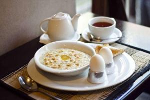 a bowl of cereal and eggs and a cup of tea at Aureliu Hotel in Krasnodar
