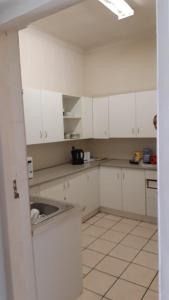 una cocina con armarios blancos y fregadero en MJ ACCOMODATION en Ciudad del Cabo