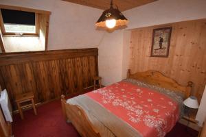 ein Schlafzimmer mit einem Bett in einem Zimmer mit Holzwänden in der Unterkunft VAUJANYLOCATIONS - Chalet Perin in Vaujany