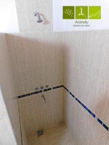 a shower in a bathroom with white tiles at Arandu ecolodge in Colonia Carlos Pellegrini