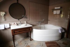 a bathroom with a tub and a sink and a mirror at Hotel Royal in Belgorod