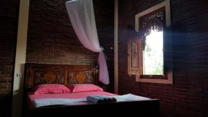 Un dormitorio con una cama con almohadas rosas y una ventana en Villa Joglo Cimande, en Bogor
