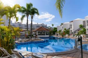una piscina con sedie e palme presso il resort di Apartamentos Parque del Sol ad Adeje