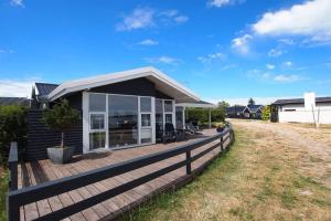 uma casa com um deque de madeira num quintal em Eksklusiv sommerhus beliggende i vandkanten em Munkebo