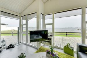 a living room with a television and a view of the ocean at Eksklusiv sommerhus beliggende i vandkanten in Munkebo