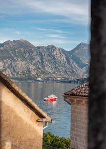 a red boat in the water with mountains at Apartment Forteca Lux in Perast