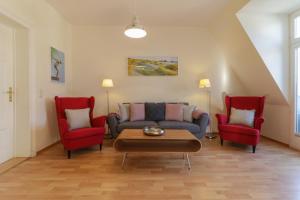 - un salon avec un canapé et deux fauteuils rouges dans l'établissement Villa Frieda, à Bansin
