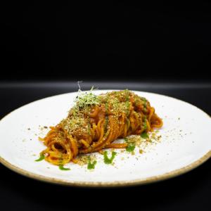 a plate of pasta with sauce and herbs on it at Warmthotel in Rome