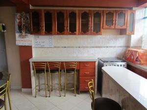 una cocina con armarios de madera y taburetes de bar en Hotel Colquewasi, en Cusco