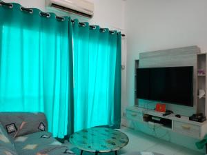 a living room with green curtains and a television at Lake Residence No165 @aesthetic lake view & best photograph in Puchong