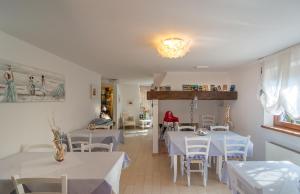 un ristorante con tavoli bianchi, sedie bianche e una persona di Villa Il Fortino a Lido di Camaiore
