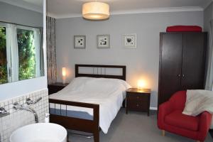 a bedroom with a bed and a red chair at Middle Farm Villa B&B in Wellingborough