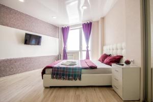 a bedroom with a bed and a window with purple curtains at Apartment Romantic Никитина 107 in Barnaul