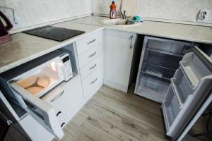 a kitchen with an open refrigerator and a sink at Apartment Romantic Никитина 107 in Barnaul