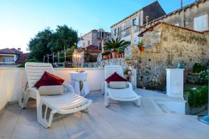 un patio con 2 sillas blancas y una mesa en Apartments Dubrovnik Seven, en Dubrovnik