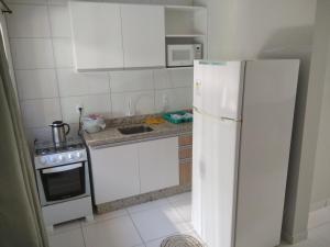 a kitchen with white cabinets and a white refrigerator at Residencial Zé Buscapé in Bombinhas