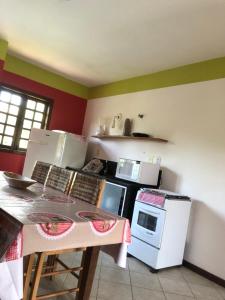 Il comprend une cuisine équipée d'une table et d'une cuisinière. four supérieur dans l'établissement La Corte Residencial AC, à Porto Seguro
