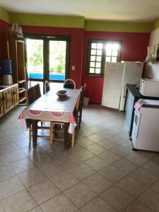 une cuisine avec une table et une cuisine aux murs rouges dans l'établissement La Corte Residencial AC, à Porto Seguro