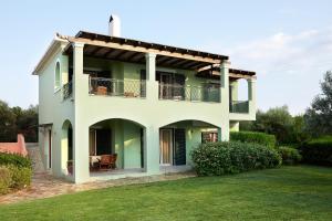 a white house with a balcony and a yard at Nymfes Villas in Porto Heli