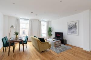 sala de estar con mesa, sillas y TV en London City Apartments - Luxury and spacious apartment with balcony, en Londres