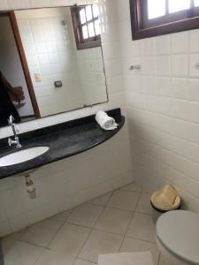 La salle de bains est pourvue d'un lavabo, d'un miroir et de toilettes. dans l'établissement La Corte Residencial AC, à Porto Seguro