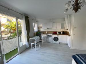 uma cozinha com armários brancos e uma mesa e cadeiras em Naïades 2 em La Baule