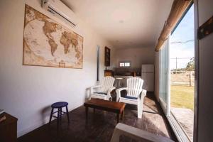 a living room with two white chairs and a table at Tiny House Necochea in Necochea