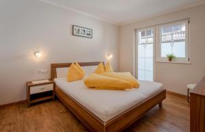 1 dormitorio con 1 cama con almohadas amarillas en Appartements KATHARINA, en Aschau