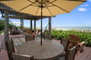 a patio area with chairs, tables and umbrellas at Beach Place Guesthouses in Cocoa Beach