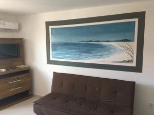 a living room with a couch and a painting on the wall at Loft Centro in Arraial do Cabo