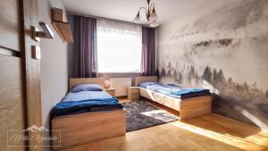 a bedroom with two beds and a painting on the wall at Willa Ramzówka - Domek w Beskidzie Sądeckim in Nowy Sącz