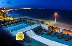 Hotel Cabo Branco Atlântico في جواو بيسوا: مسبح وكراسي وشاطئ بالليل