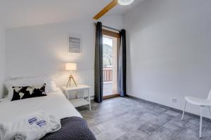 a bedroom with a bed and a table and a window at Bailicîmes Apartment - Snow and Trek - Morzine in Morzine