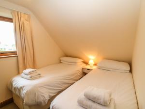 two twin beds in a small room with a window at Granary Cottage in Shipston on Stour