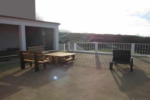 una terraza con 2 bancos y una mesa y sillas de madera. en Cantinho da Ilha en Achadinha