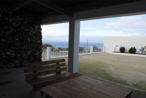 un banco de madera en un balcón con vistas al océano en Cantinho da Ilha, en Achadinha