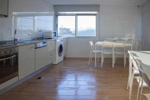cocina con mesa y sillas y cocina con lavadora en Central Suites 3, en São João da Madeira