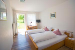 Schlafzimmer mit einem Bett mit weißer Bettwäsche und rosa Kissen in der Unterkunft Landgasthof Schwanen in Ostrach